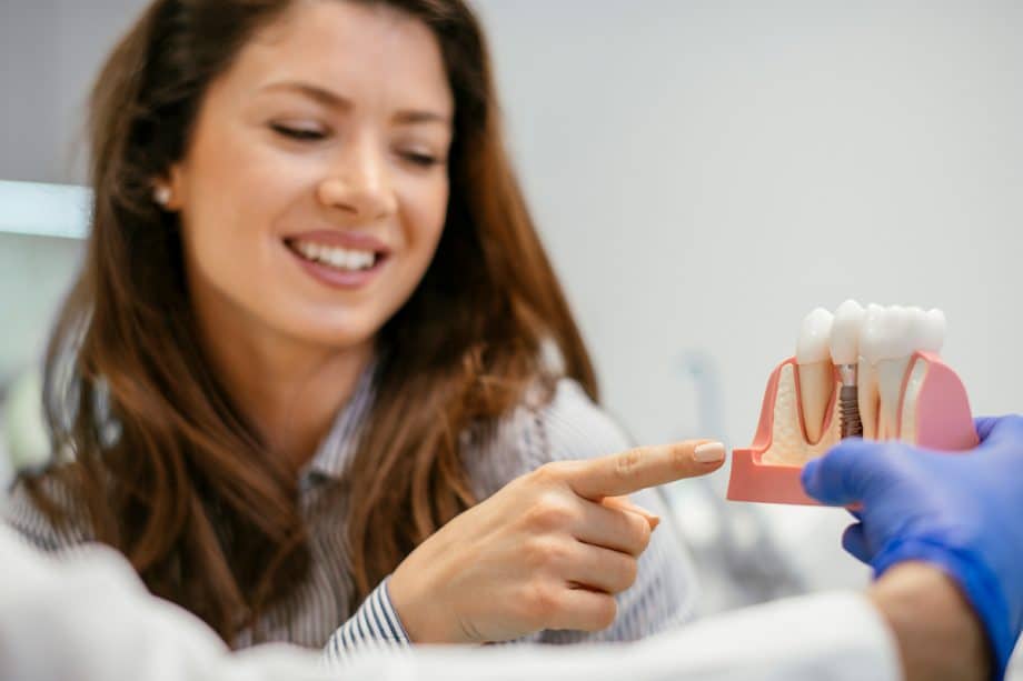 woman pointing to model of dental implant