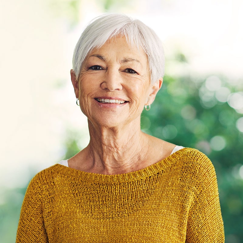 senior woman wearing yellow sweater, smiling