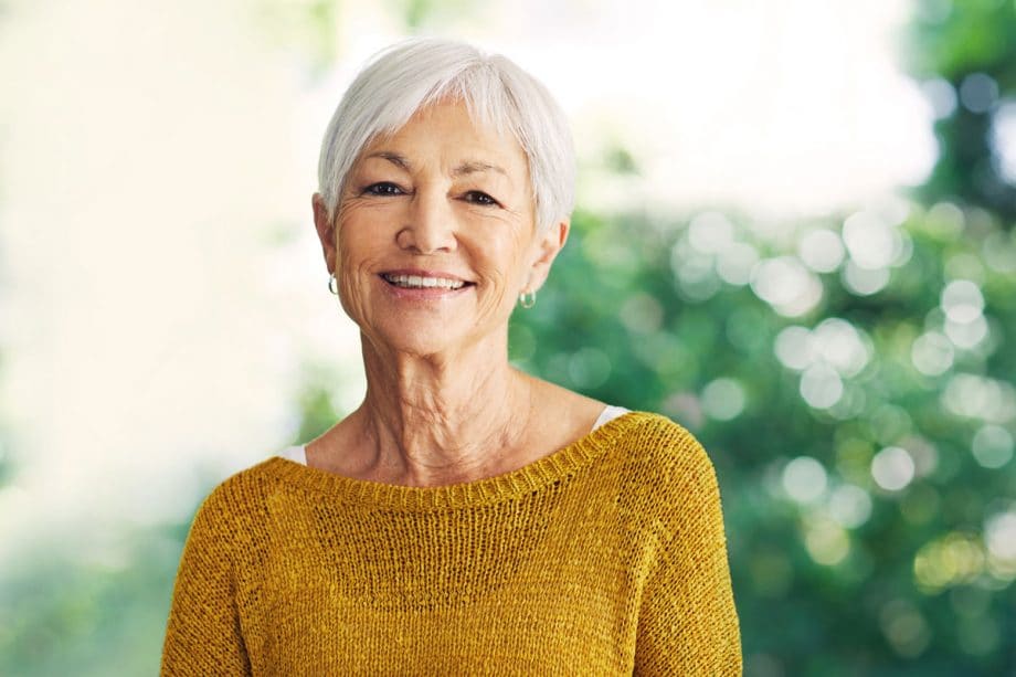 senior woman wearing yellow sweater, smiling