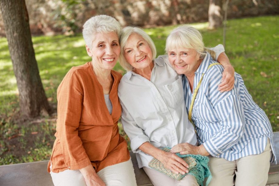 three senior woman in park, sitting on cement bench