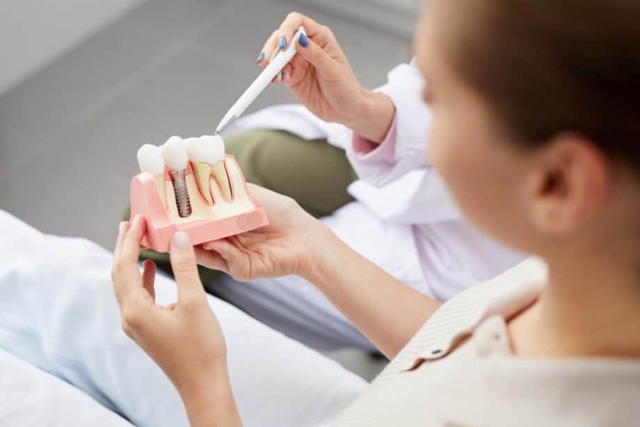 woman holding model of dental implant