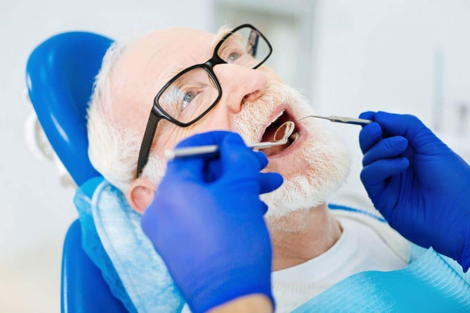 older man in dental chair getting dental exam