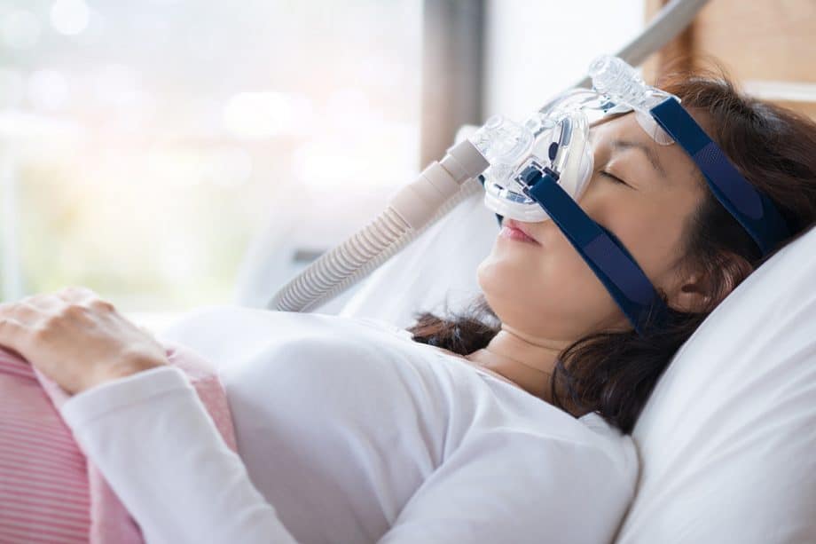 woman sleeping in bed wearing a CPAP