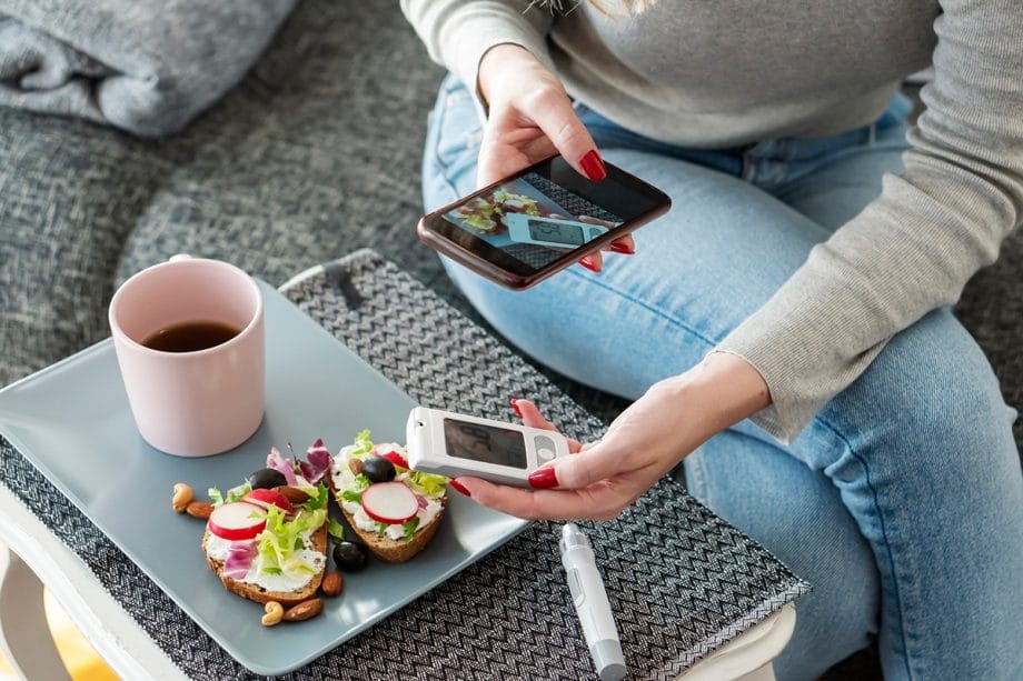 woman taking a cell phone picture of her lunch and blood sugar device