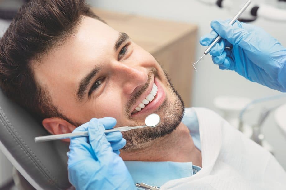 hands of dentist holding tools over male dental patient